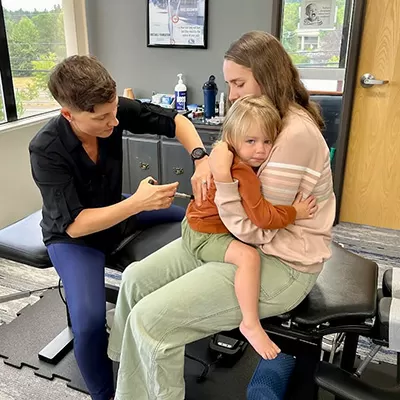 Chiropractor Tigard OR Jessica Hudson Adjusting Child On Moms Lap